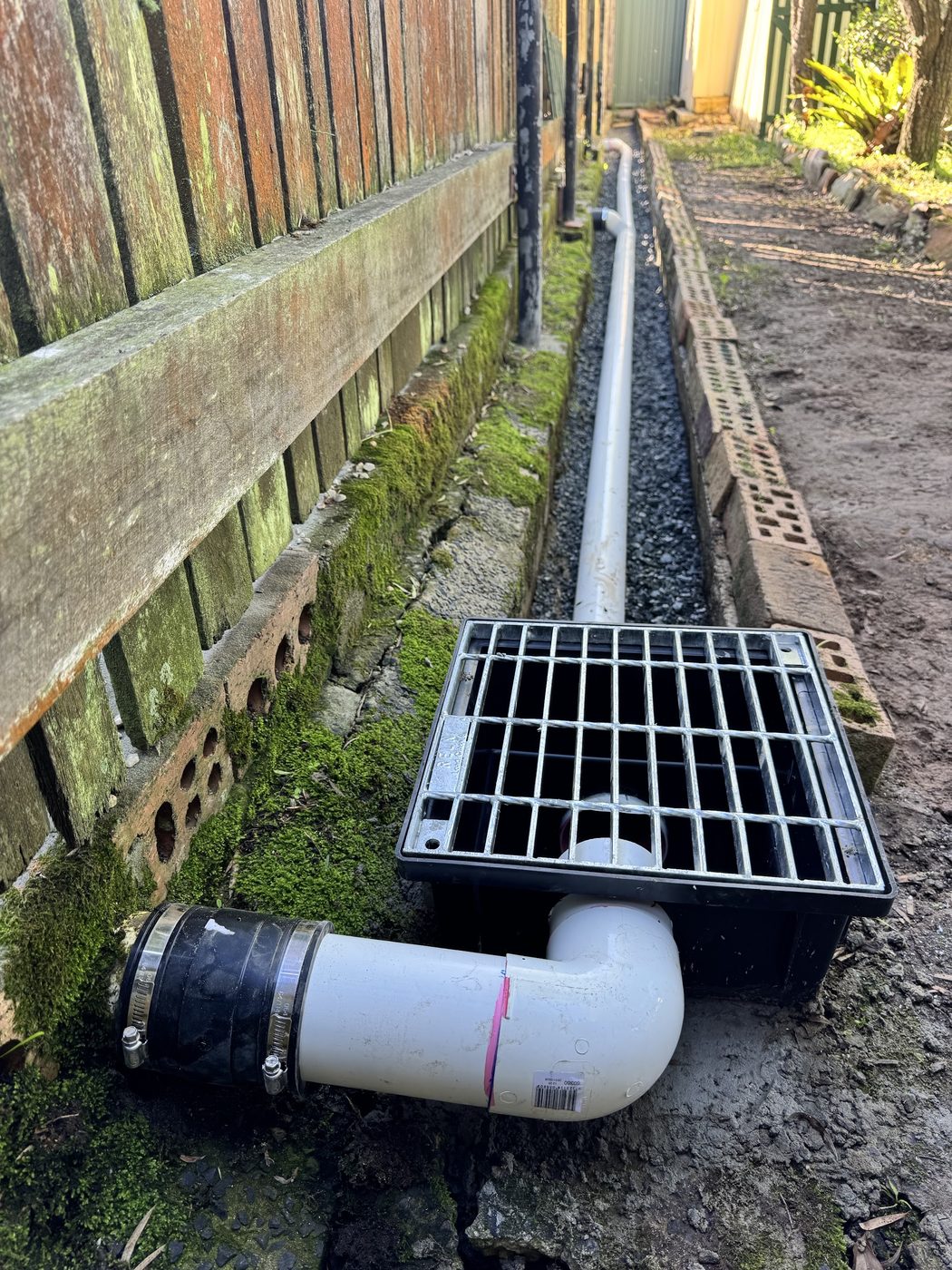 A new stormwater grate and pit set into a gravel backfilled trench beside a path